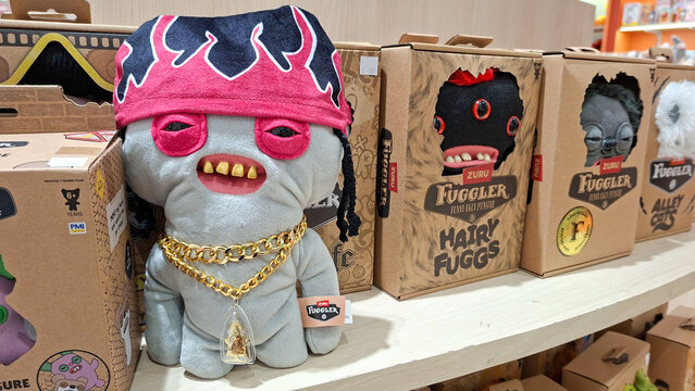 Fuggler funny ugly monster plush toy with red bandana and gold chain accessory on store shelf display on April 4, 2026 in Bangkok, Thailand.