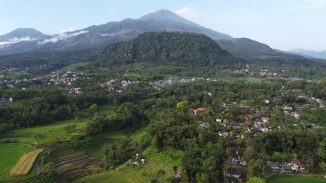 Aerial view of Mount Welirang with terraced rice fields, rural village settlement, and green valley landscape in East Java, Indonesia