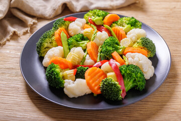 plate of mix of steamed vegetables on wooden table