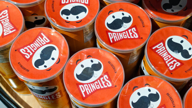 High angle view of multiple Pringles potato chips cans with orange lids and iconic mascot logo arranged in a cluster on a store shelf on September 17, 2025 in Bangkok, Thailand.