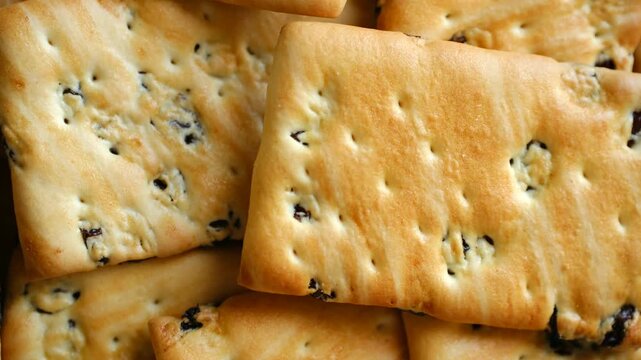 Delicious crispy golden crackers with sweet raisins rotating in a delightful macro view, showcasing the tasty texture of the baked snack food for a satisfying and crunchy treat