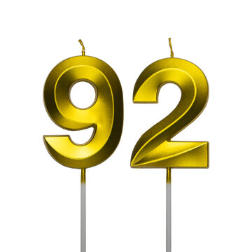 A pair of shiny golden birthday candles in the shape of the number ninety two, featuring a spiral textured surface and isolated on a plain white background.