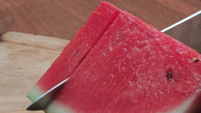 Cutting watermelon with a knife.