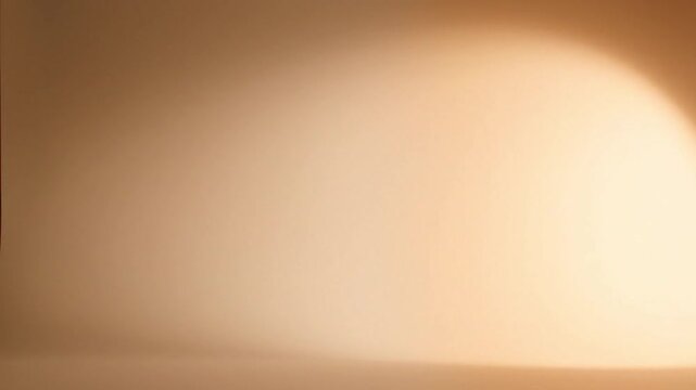 Warmly lit abstract background with a smooth gradient transitioning from dark to light beige tones.