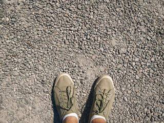 Olive green canvas sneakers on gravel surface - casual streetwear, top view.