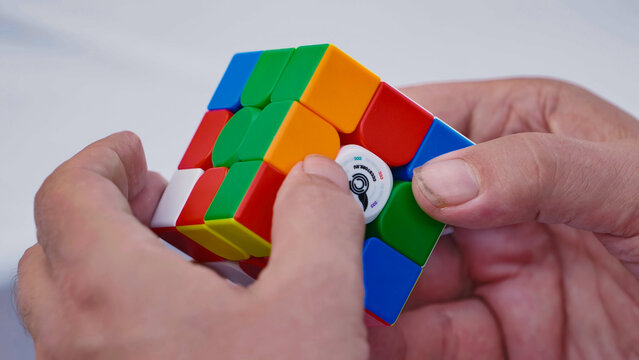 Moscow, Russia - July 5, 2025: Hands solving colorful Rubik's cube, logic game and intellectual challenge