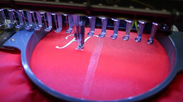Machine embroidery on red fabric with white thread. Text embroidery. Close up 4k video