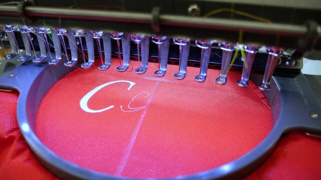 Machine embroidery on red fabric with white thread. Text embroidery. Close up 4k video
