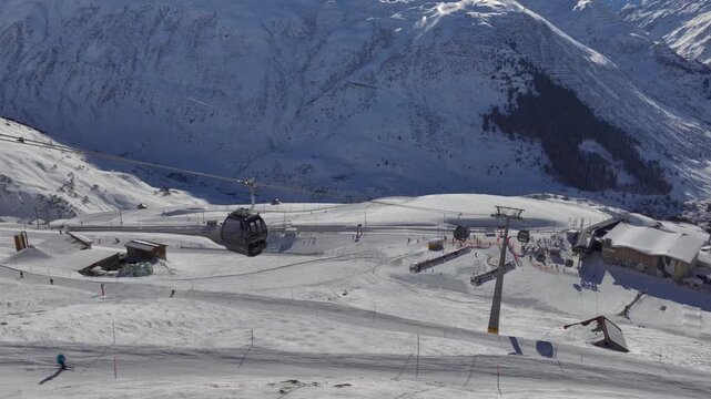 Andermatt Ski Resort in Switzerland. People Tourists riding skiing Snowboarding on snow-covered Slope, Aerial Drone View