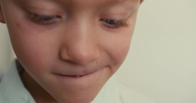 Close-up of a boy face with his first baby tooth wobbling. He plays with his lips and moves the tooth, trying to get rid of it faster. Children dental hygiene.