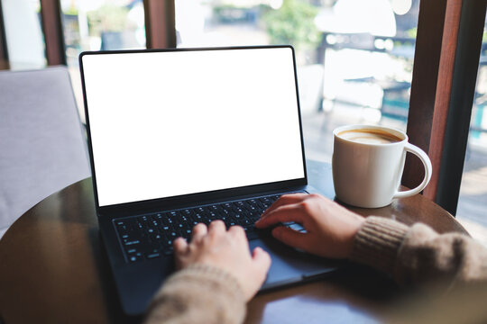 Mockup image of a woman working and typing on laptop computer with blank white desktop screen in cafe