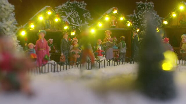 Close-up of a charming miniature Christmas village. Figurines skate in a snowy town square in front of warmly lit market stalls. A magical, festive, and nostalgic holiday diorama