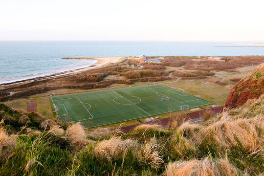 Aerial View Of Coastal Football Field Near Red Cliffs And Ocean