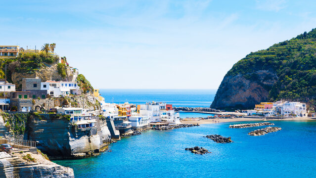 Picturesque coastal village of Sant'Angelo on Ischia Island, Italy with colorful buildings on cliffs and turquoise Mediterranean waters. Green mountain rises from sea, beautiful coastal landscape