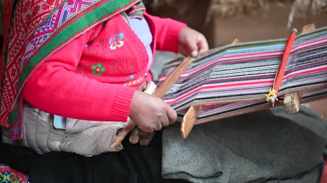 A Peruvian woman wearing traditional Andean clothing is hand-weaving textiles, showcasing local craftsmanship, cultural heritage, and vibrant indigenous fabric artistry.