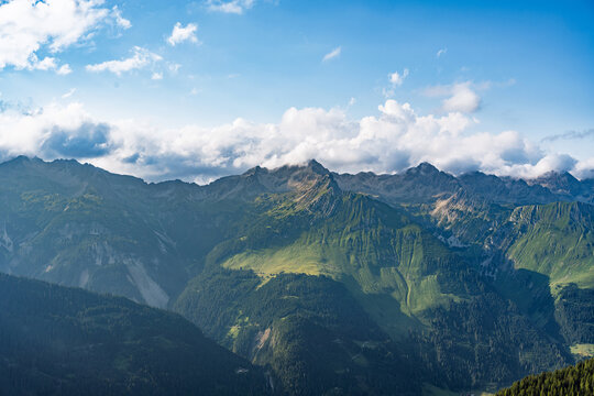 Scenic view across the valley towards the Hornbachkette peaks in the Lechtal Alps, Tyrol. Panoramic summer mountain landscape with a cloudy blue sky. Pure alpine wilderness, Austria.
