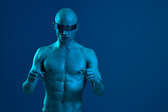 Athletic man in futuristic sunglasses, showcasing a unique style and bold vibe, captured against a blue background, exuding confidence and strength.