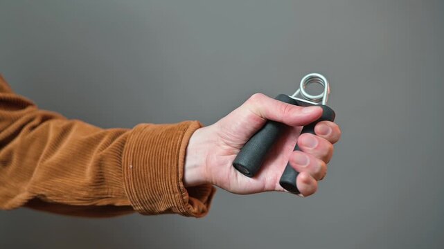A hand holds a grip strengthener while performing exercises to enhance hand strength. This action is suitable for anyone looking to improve hand function, regardless of age or background