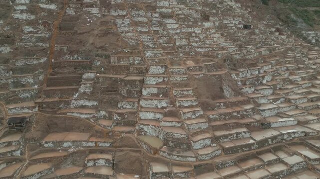 Drone aerial view of the Maras Salt Mines, with terraced salt ponds covering the hillside in the Sacred Valley of Peru