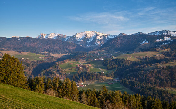 Spring landscape at the foot of the Nagelfluhkette with the snow-covered Hochgrat peak above Steibis near Oberstaufen in the Allg&auml;u region of Bavaria, Germany, under soft afternoon light.
