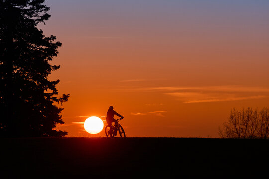 Woman with a mountain bike enjoying a scenic sunset in the Allg&auml;u region, Germany. Outdoor adventure, freedom, and active lifestyle in a peaceful alpine landscape with warm evening light.