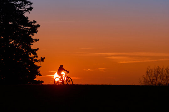 Woman with a mountain bike enjoying a scenic sunset in the Allg&auml;u region, Germany. Outdoor adventure, freedom, and active lifestyle in a peaceful alpine landscape with warm evening light.