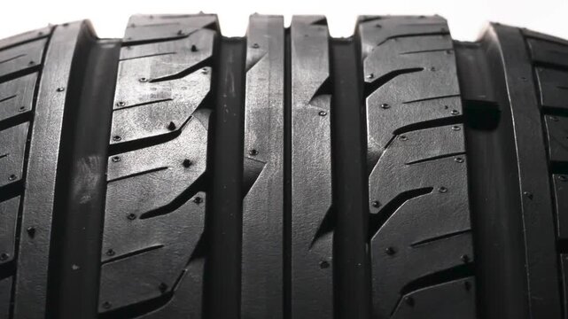 Wheel Tread Pattern in Motion. New car wheel close-up slowly spinning showing tread pattern on white background