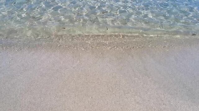 Gentle ocean waves rolling onto a sandy beach, creating foam and ripples as the tide ebbs and flows in a serene coastal environment