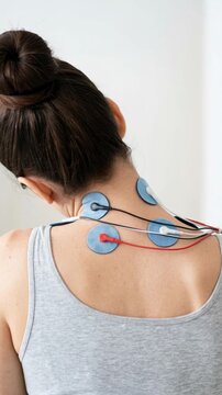 Woman receiving electrical muscle stimulation therapy on her neck for pain relief and rehabilitation