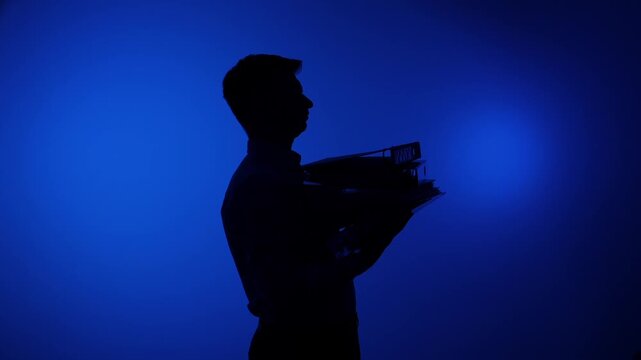 Silhouette of a man managing heavy office paperwork, carrying a large stack of document binders against a blue background, representing workload and business challenges