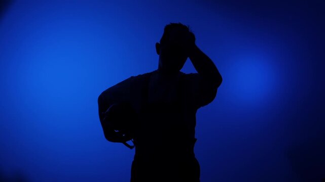 Industrial worker silhouette standing confidently with hands on hips against a vibrant blue background, conveying strength, professionalism, and determination in the workplace