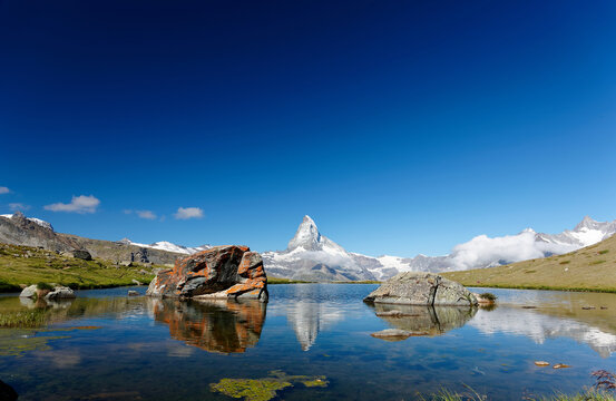Scenery of the iconic Matterhorn mountain on a beautiful summer morning, with its pyramidal peak reflected in the quiet water of Lake Stellisee under blue clear sky in Zermatt, Valais, Switzerland