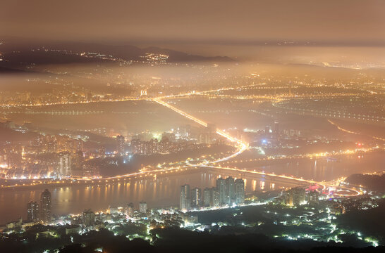 Top view of Taipei on a foggy winter evening, the vibrant capital city of Taiwan, with lights of buildings, streets & bridges glowing in the mist~Scenery Taipei City in dense fog & ethereal atmosphere