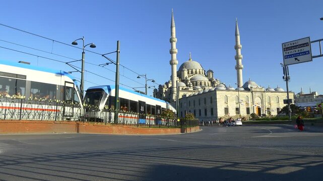 Modern tram runs in front of Valide Sultan Mosque at Eminonu Square in Istanbul. Yenicami Mosque