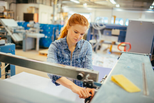 Female technician operating printing machine in factory
