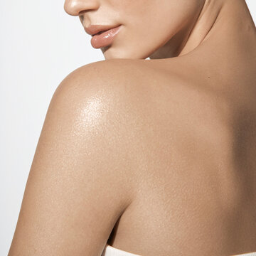 Close up of smooth glowing skin on female shoulder with subtle shimmer and glow.