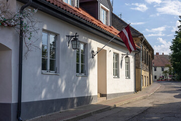Fototapeta premium Charming street view in Cesis Latvia captures the essence of a peaceful afternoon with a Latvian flag waving gently