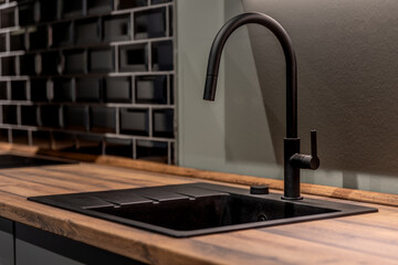 Modern kitchen sink with black faucet and wooden countertop. Stylish minimal kitchen interior design