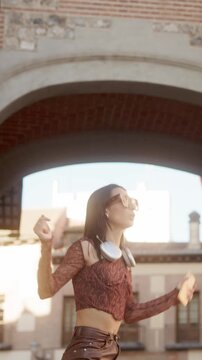Happy young woman dancing listening to music in the street