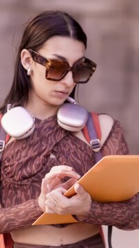Young female student checking documents walking outdoors