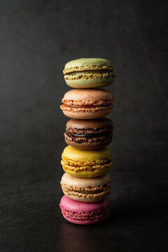 Stack of multi colored and flavored macaroons on a dark surface 
