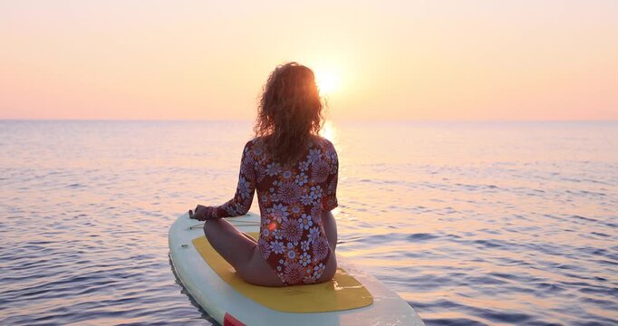 Young woman walking on sup board by the sea during summer vacation. Slow motion