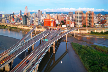 Fototapeta premium Top view of Zhongxing Bridge spanning Tamsui River & connected to the riverside Huanhe Expressway with crowded buildings in Ximending Downtown & 101 Tower standing in background in vibrant Taipei City