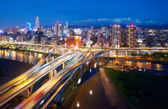Night view of Zhongxing Bridge over Tamsui River & slip roads to the riverside Huanhe Expressway, with crowded buildings in Ximending Downtown & 101 Tower standing in background in vibrant Taipei City