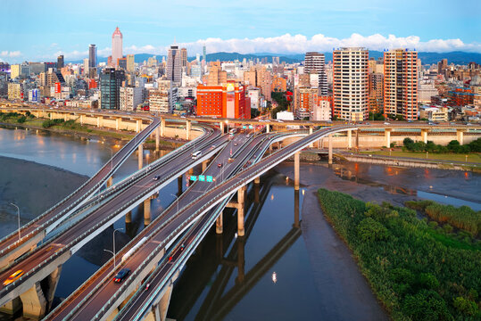Top view of Zhongxing Bridge spanning Tamsui River & connected to the riverside Huanhe Expressway with crowded buildings in Ximending Downtown & 101 Tower standing in background in vibrant Taipei City
