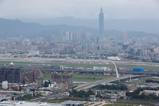 Panoramic aerial view of busy Taipei city, Keelung river, Dazhi Bridge, Songshan Airport and Taipei 101 at dusk ~ A romantic evening in Taipei Taiwan, with beautiful blue gloomy mood in the sky