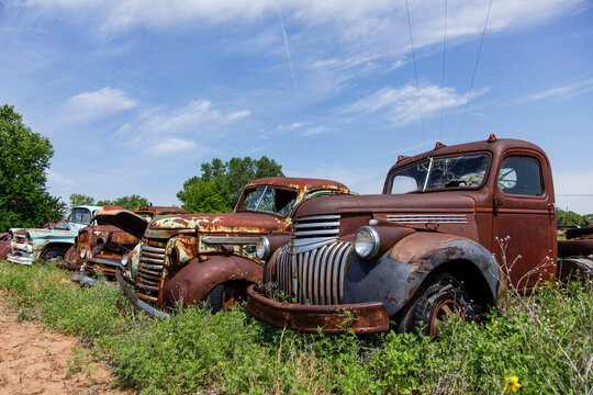 Row of rusted vintage trucks in abandoned junkyard Route 66 landscape 