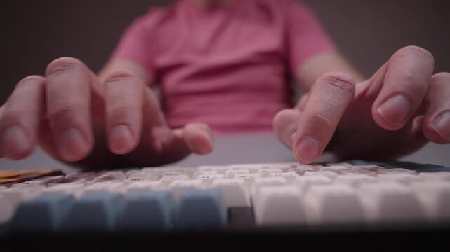 Close-up of male hands typing on wireless mechanical keyboard. Low angle view of unrecognizable man pressing keys on custom computer peripheral for gaming and programming. Shooting in slow motion.