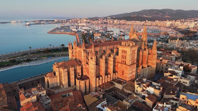 Aerial view of Santa Maria Cathedral in Palma de Mallorca at sunrise, golden morning light over the historic landmark. Majestic gothic cathedral La Seu with a harbor backdrop, Mallorca
