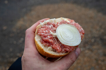 Half a raw minced pork roll with onions in the hand